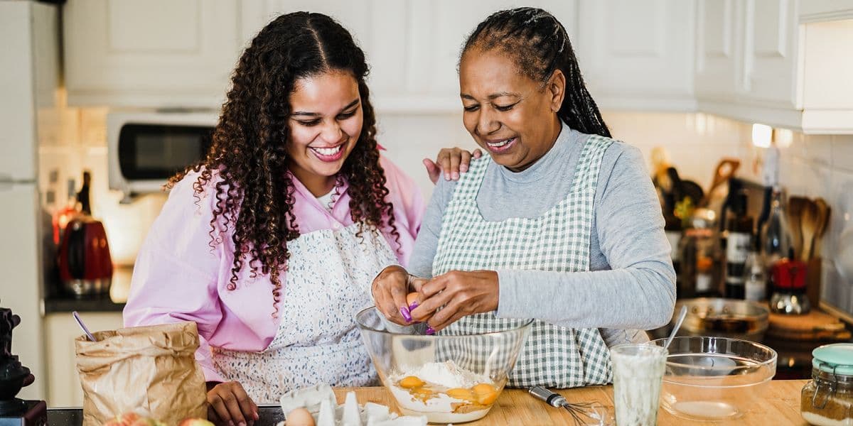 senior woman and daughter cooking together in kitchen