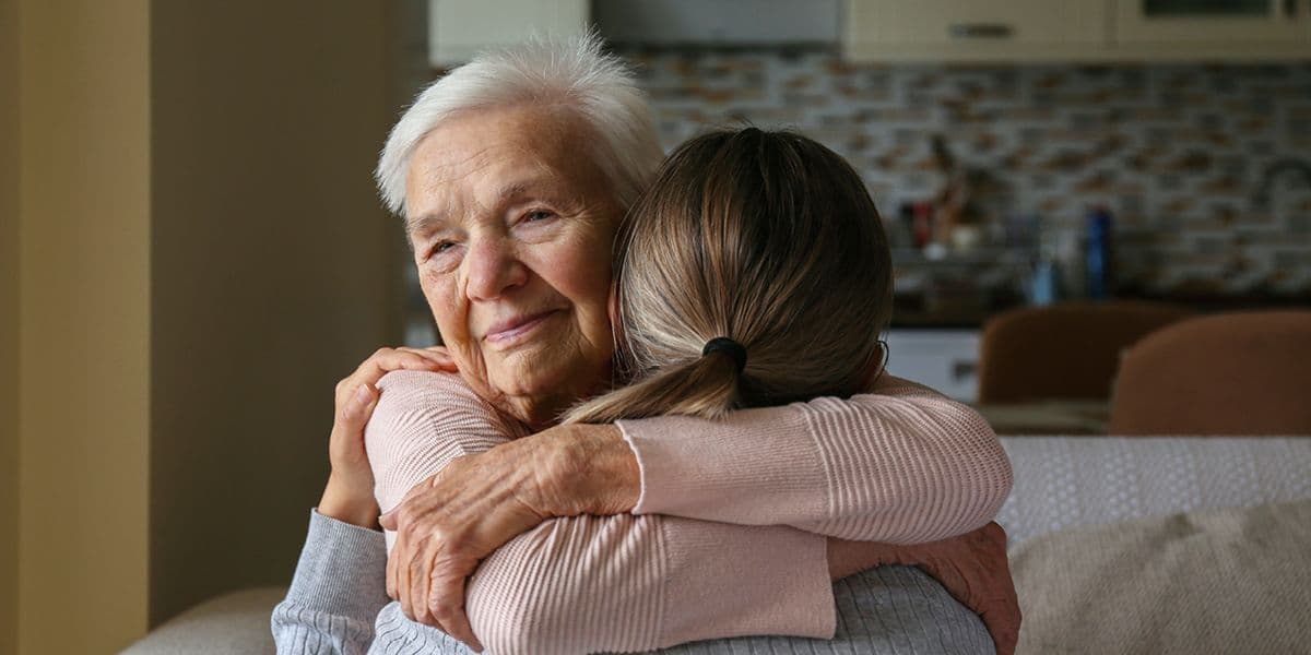senior woman being comforted by family