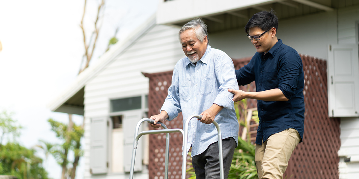 Caregiver son assisting father on walker